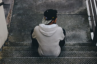 Man sitting alone on metal stairs from behind