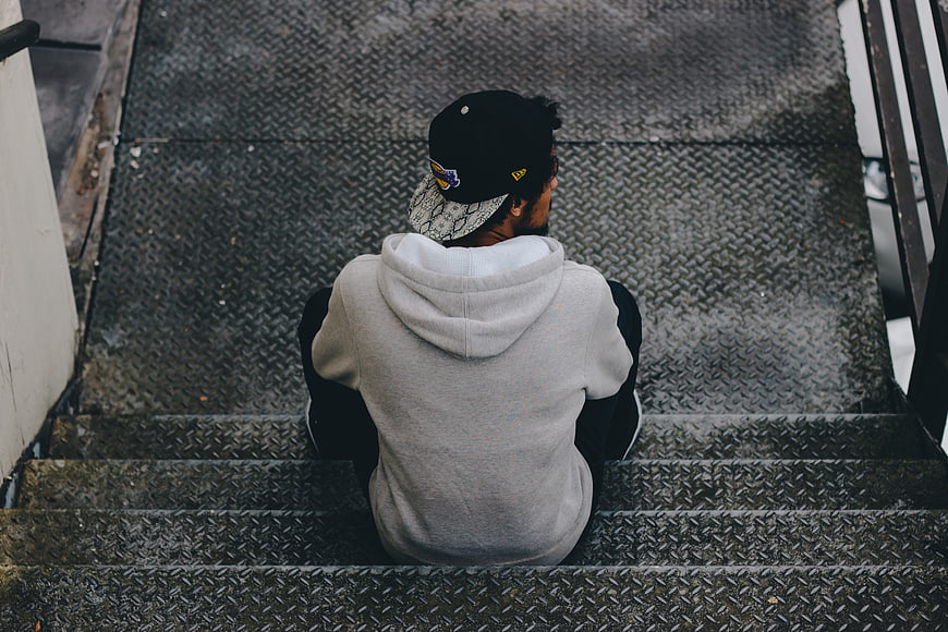 Man sitting alone on metal stairs from behind