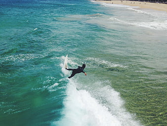 Surfer Riding Wave in Turquoise Ocean