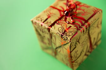 Wrapped Gift Box with Red Ribbon on Green Background