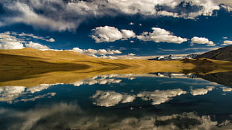 Serene Highland Lake with Cloud Reflections and Distant Mountains