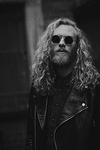 Black and white portrait of man with long curly hair and sunglasses