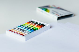 Box of colorful oil pastels on white paper