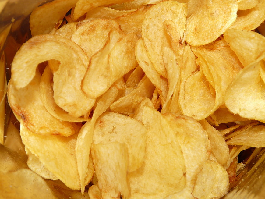 Close-up of golden fried potato chips in a bag
