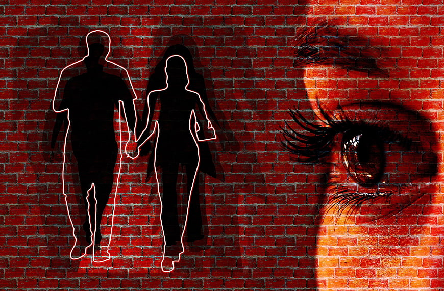 Silhouetted Couple Walking Against Red Brick Wall With Close-Up Eye