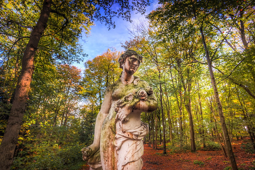 Weathered Stone Statue in Autumn Forest Park
