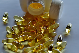 Spilled Golden Vitamin Capsules From White Plastic Bottle