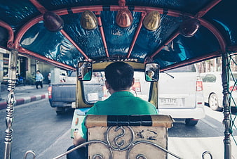 Rear view of a tricycle driver on a busy street