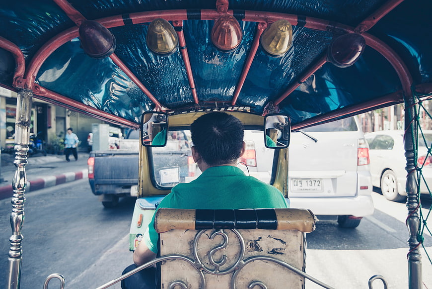 Rear view of a tricycle driver on a busy street
