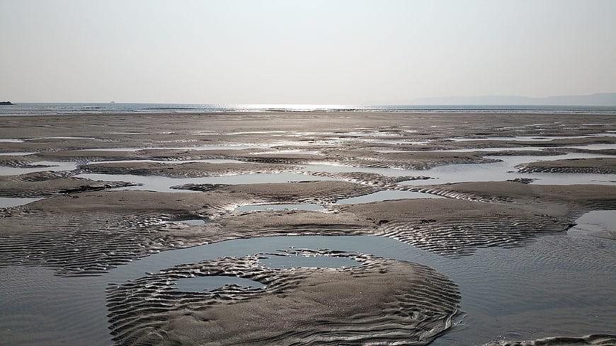 Wide tidal flats with rippled sand patterns and distant ocean horizon