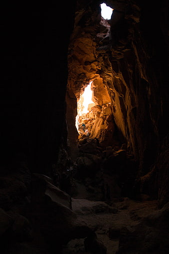 Hikers Exploring a Dark Cave with Bright Natural Light Opening