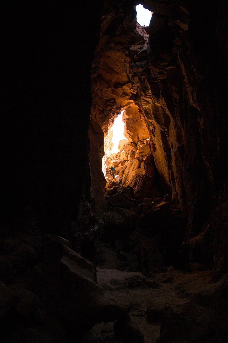 Hikers Exploring a Dark Cave with Bright Natural Light Opening