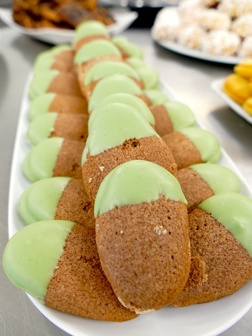 Rows of green dipped ladyfinger cookies on white platter