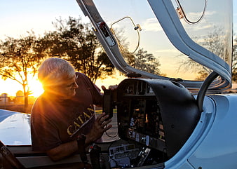 Senior man inspecting aircraft cockpit at sunset