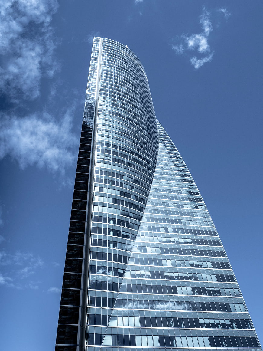 Low angle view of modern twisted glass skyscraper