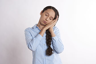 Tired young woman with closed eyes and hands on face