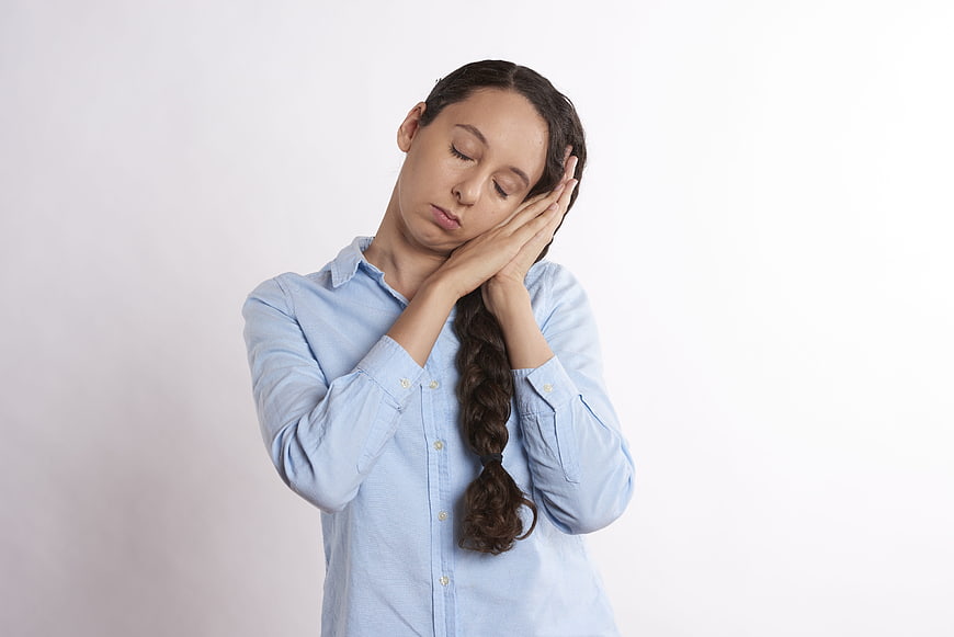 Tired young woman with closed eyes and hands on face
