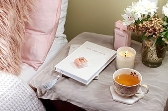 Romantic engagement ring on book with tea and flowers