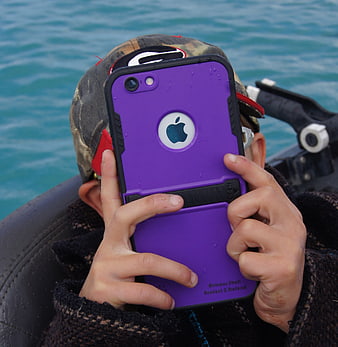 Child holding purple smartphone in boat on water