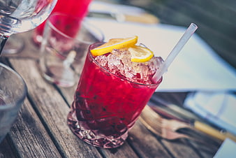 Refreshing red cocktail with lemon slices on rustic wooden table