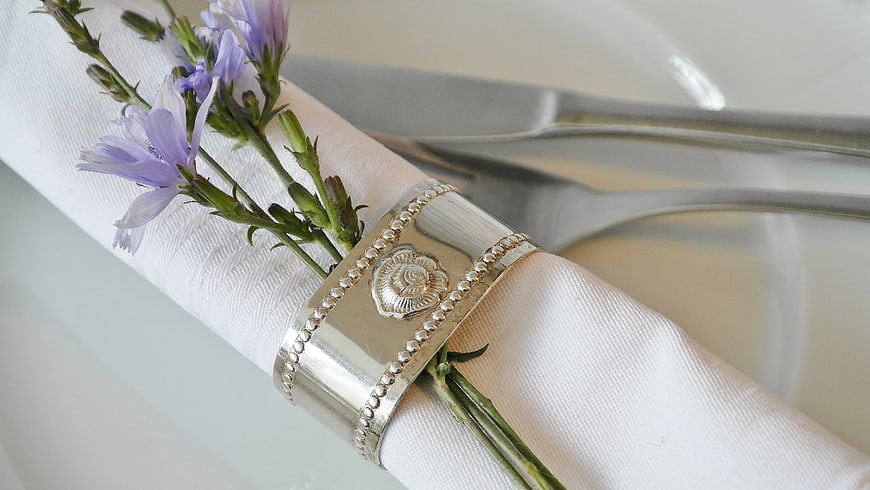 Elegant silver napkin ring with purple flowers on white table setting