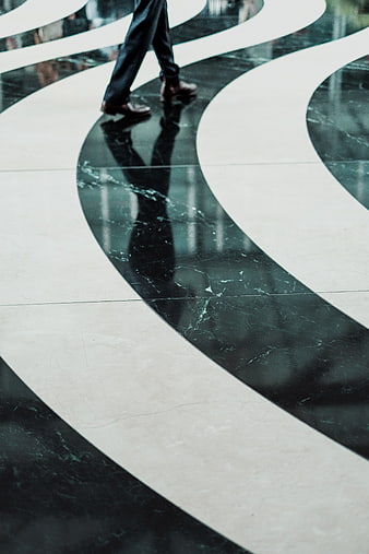 Businessman walking on polished marble floor with reflection