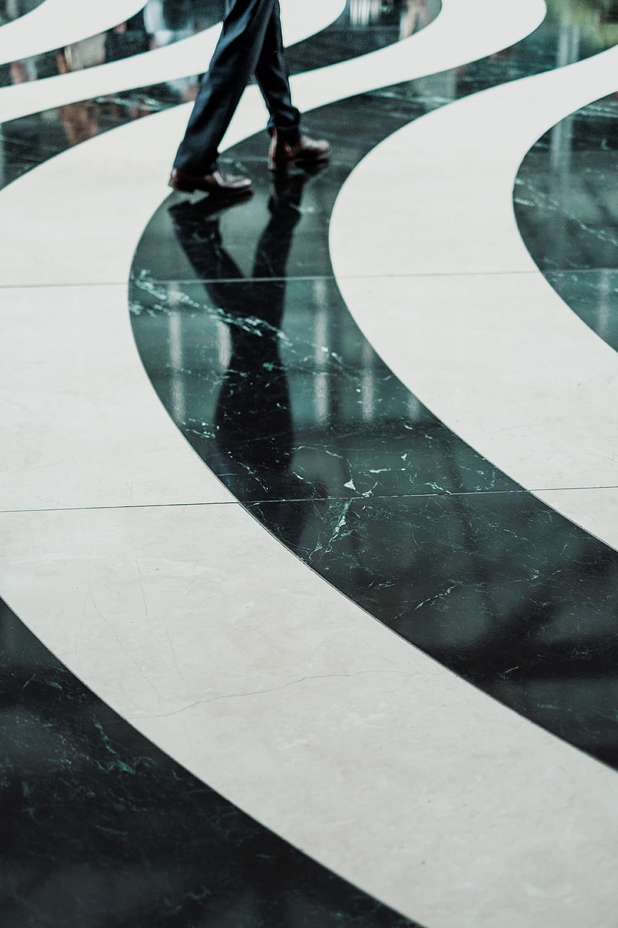 Businessman walking on polished marble floor with reflection