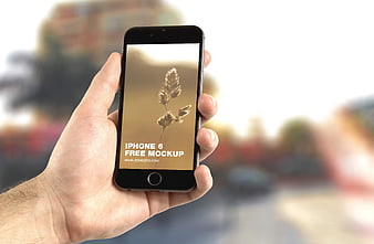 Hand holding iPhone 6 mockup with blurred city background