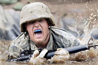 Soldier in muddy water with rifle and mouthguard