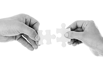 Two Hands Connecting White Puzzle Pieces on White Background