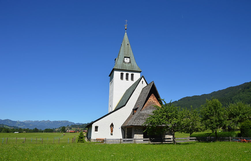 White Chapel with Green Spire in Alpine Meadow