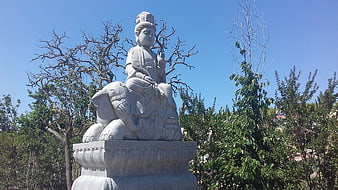 Stone statue of deity riding elephant in garden