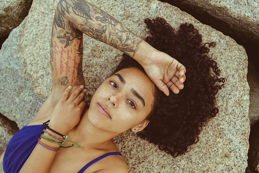 Portrait of tattooed woman lying on rocks