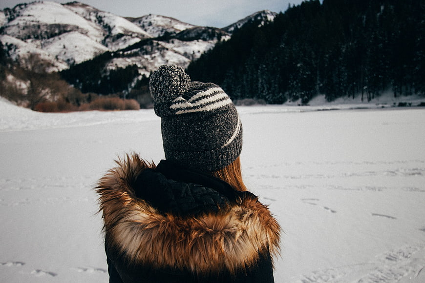 Woman in winter hat looking at snowy mountain landscape