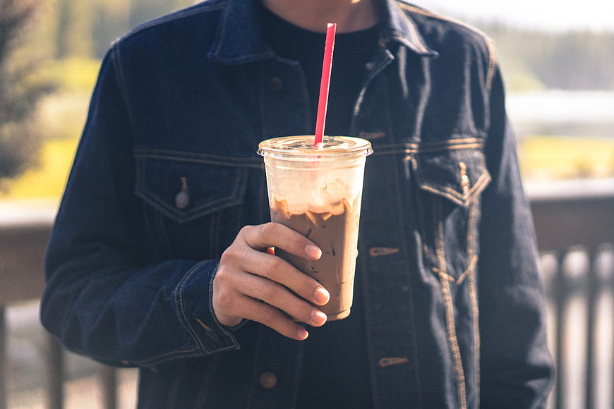 Man in Denim Jacket Holding Iced Coffee