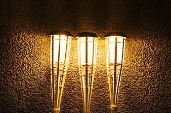 Three glowing bamboo-style lanterns against a textured wall