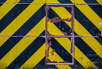 Rusty metal door with yellow and black hazard stripes