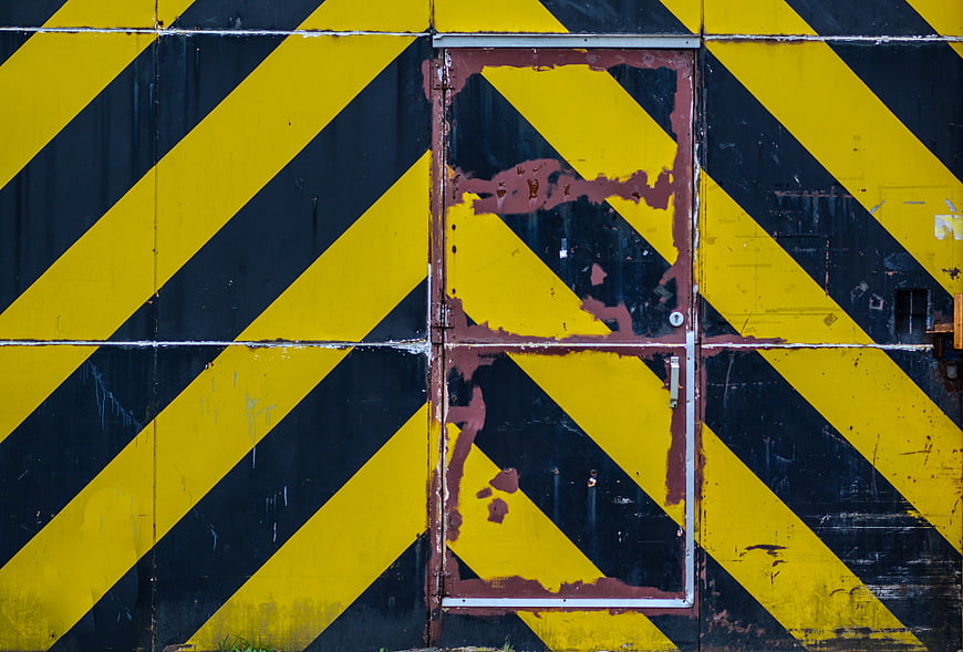 Rusty metal door with yellow and black hazard stripes