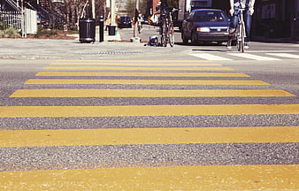 Low angle view of yellow striped crosswalk on city street