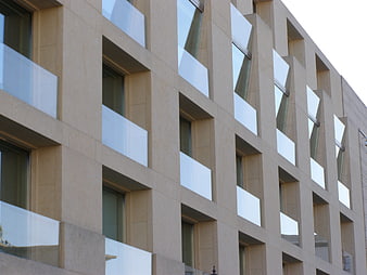 Modern beige building facade with geometric windows and glass balconies