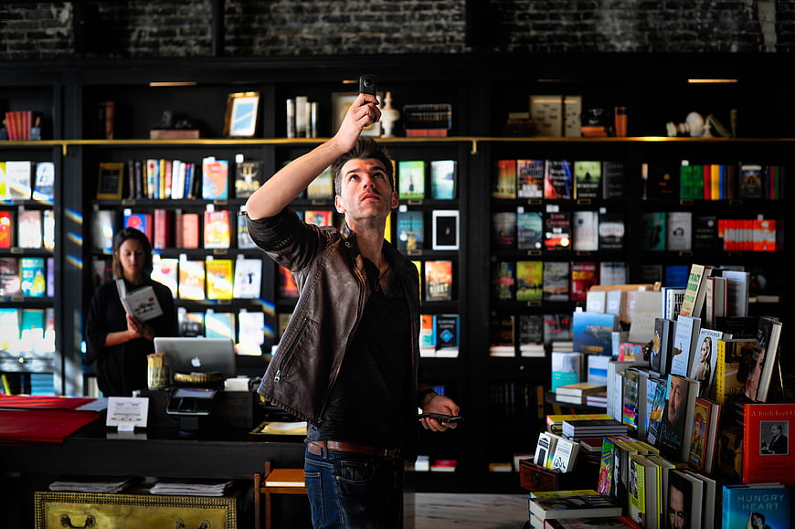 Man taking selfie in bookstore with books