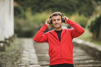 Smiling Man in Red Hoodie Listening to Music Outdoors