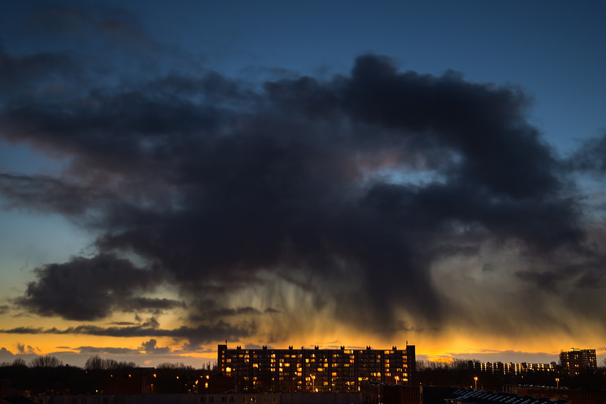 Dramatic storm clouds over urban apartment buildings at sunset