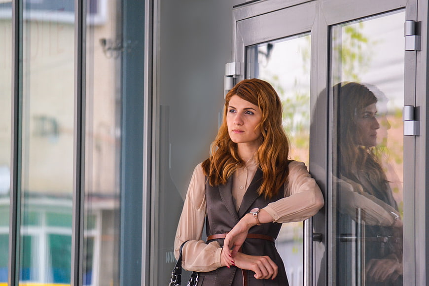 Professional Business Woman Checking Watch by Glass Door