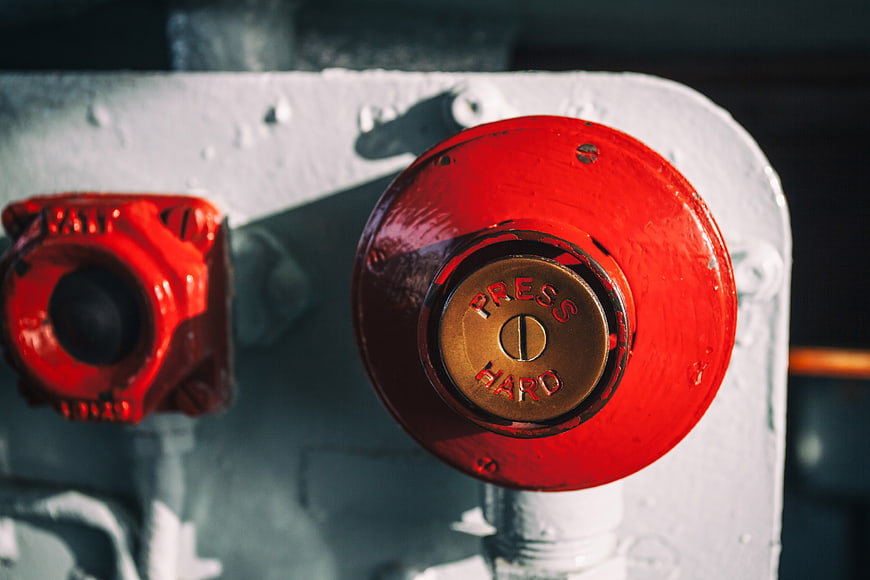 Close-up of red industrial button with press hard text on white panel