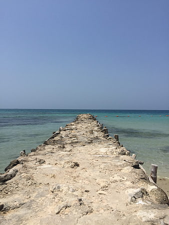 Weathered concrete pier extending into turquoise ocean water