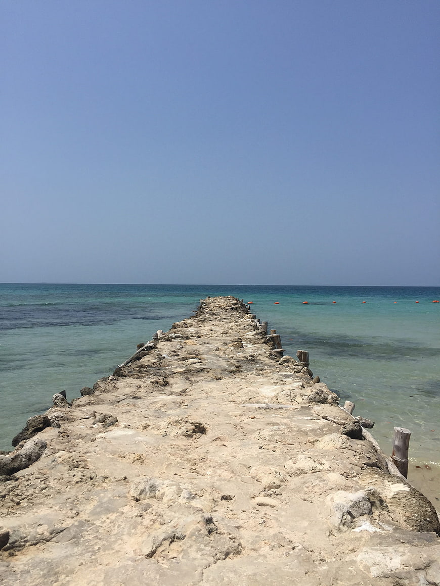 Weathered concrete pier extending into turquoise ocean water
