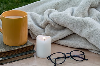 Cozy reading setup with candle, books, and mug