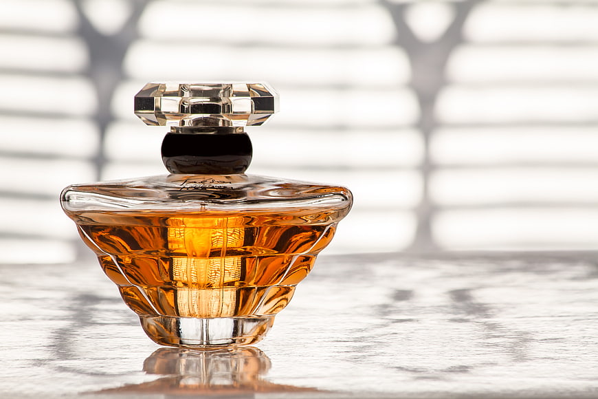 Luxury Amber Perfume Bottle With Faceted Cap On Textured Surface
