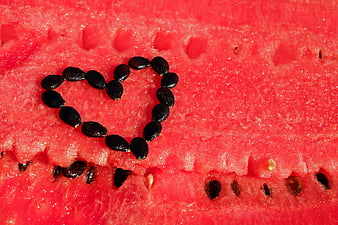 Watermelon seeds arranged in a heart shape on red fruit